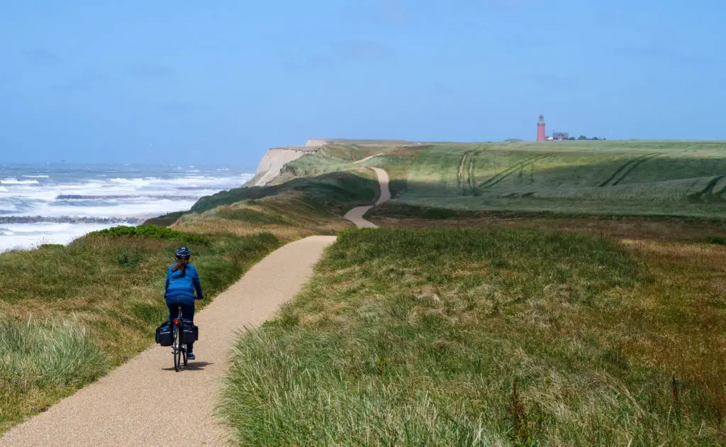 Radfahren entlang der Küste mit dem Leuchtturm von Lodbjerg im Hintergrund, Dänemarks Westküste.