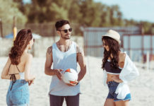 Freunde spielen Volleyball am Strand.