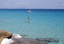 Die Nachbarinsel: Was man bei einem Tagesausflug oder Kurzaufenthalt von Ibiza aus auf Formentera unternehmen kann. SUP und Segelyacht auf Formentera, Spanien.