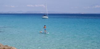 Die Nachbarinsel: Was man bei einem Tagesausflug oder Kurzaufenthalt von Ibiza aus auf Formentera unternehmen kann. SUP und Segelyacht auf Formentera, Spanien.