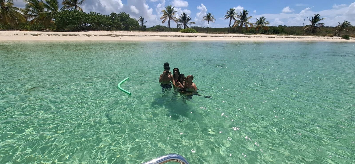 Gäste genießen das flache türkisfarbene Wasser neben einem weißen Sandstrand auf Anguilla