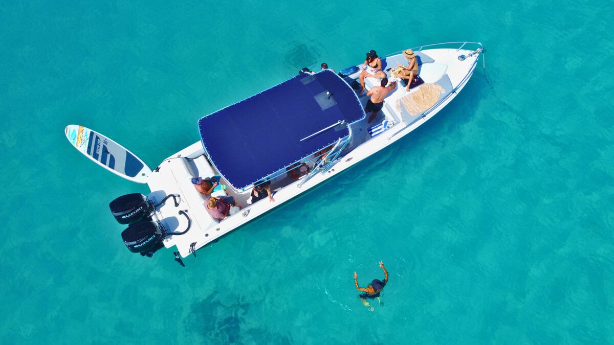 Luftaufnahme von Gästen, die einen privaten Bootscharter im türkisfarbenen karibischen Wasser genießen